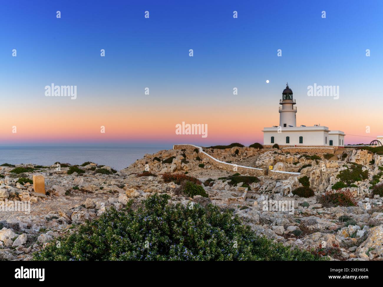 Vista del faro di Cap de Cavalleria a Minorca al tramonto con una luna piena che si innalza Foto Stock