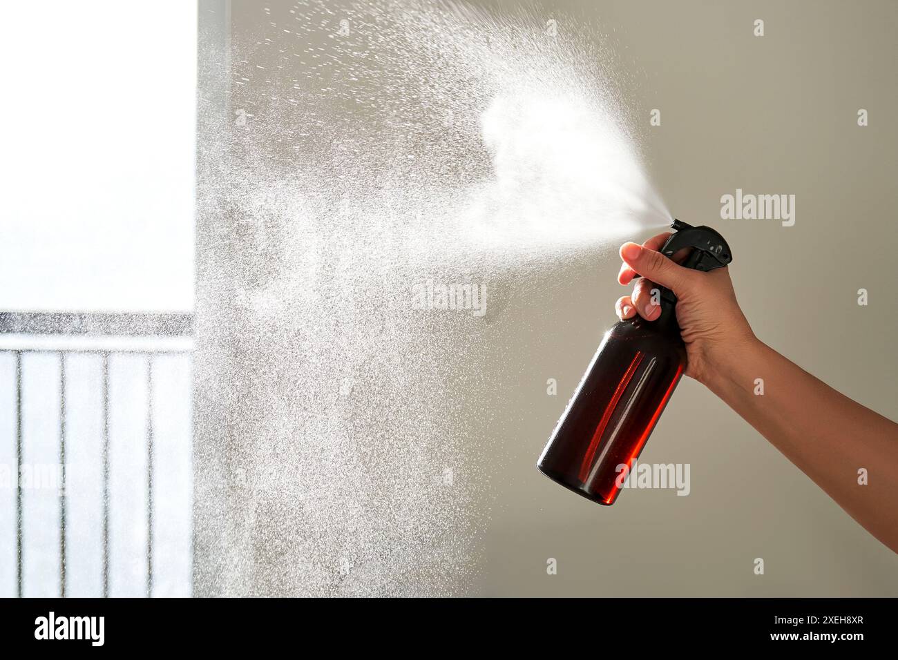 La mano di una donna spruzza un deodorante per ambienti in una stanza. Foto Stock