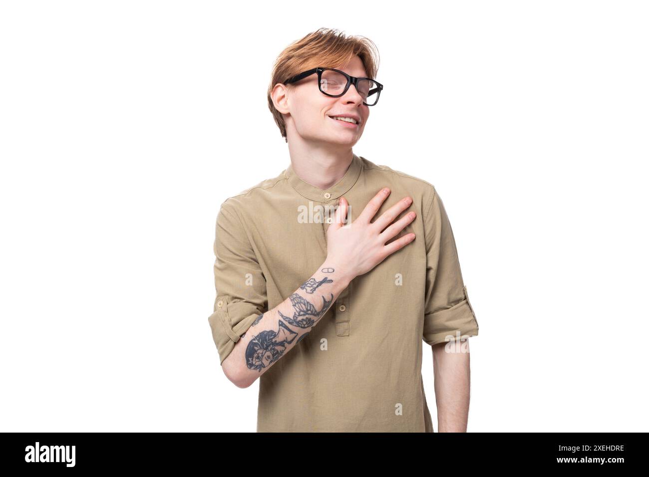 Il giovane e bellissimo uomo con i capelli di rame e un tatuaggio sul braccio indossa una camicia marrone Foto Stock