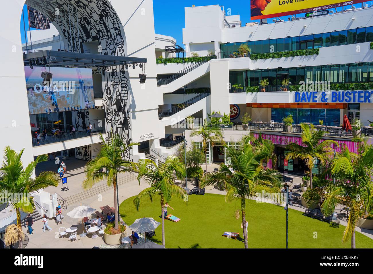 Los Angeles, California - 10 aprile 2024: Cortile aperto con lussureggiante erba verde, panchine e persone impegnate in attività presso il centro commerciale FIGat7th Foto Stock