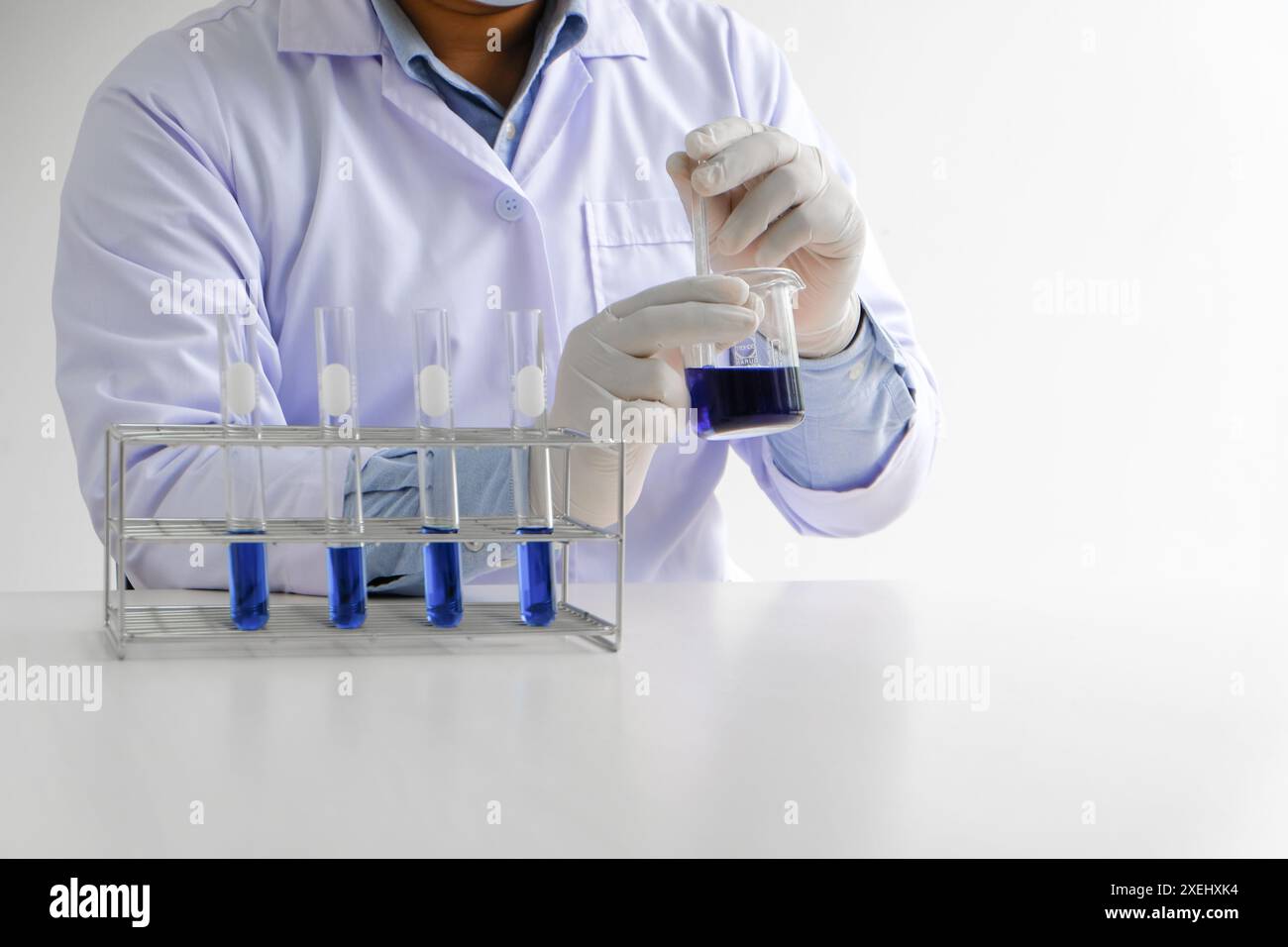 Scienza innovativa maschio medico o ricercatore di laboratorio scientifico esegue test con liquido blu in laboratorio. attrezzatura sci Foto Stock