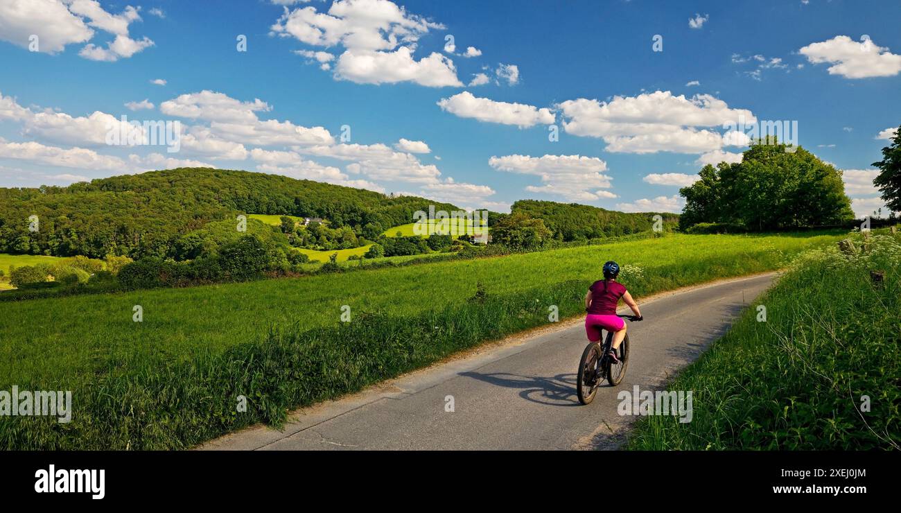 Ciclista in un paesaggio collinare con cielo blu e nuvole, Wetter (Ruhr), regione della Ruhr, Germania, Europa Foto Stock