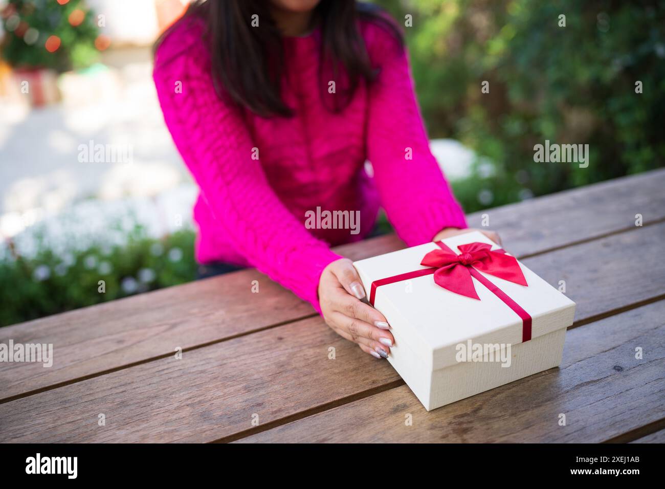 Le mani di una donna asiatica felice ed eccitata tengono in mano una confezione regalo di Natale. Allegra ragazza che porta il regalo di Natale o il compleanno di Natale boxÂ Natale Foto Stock