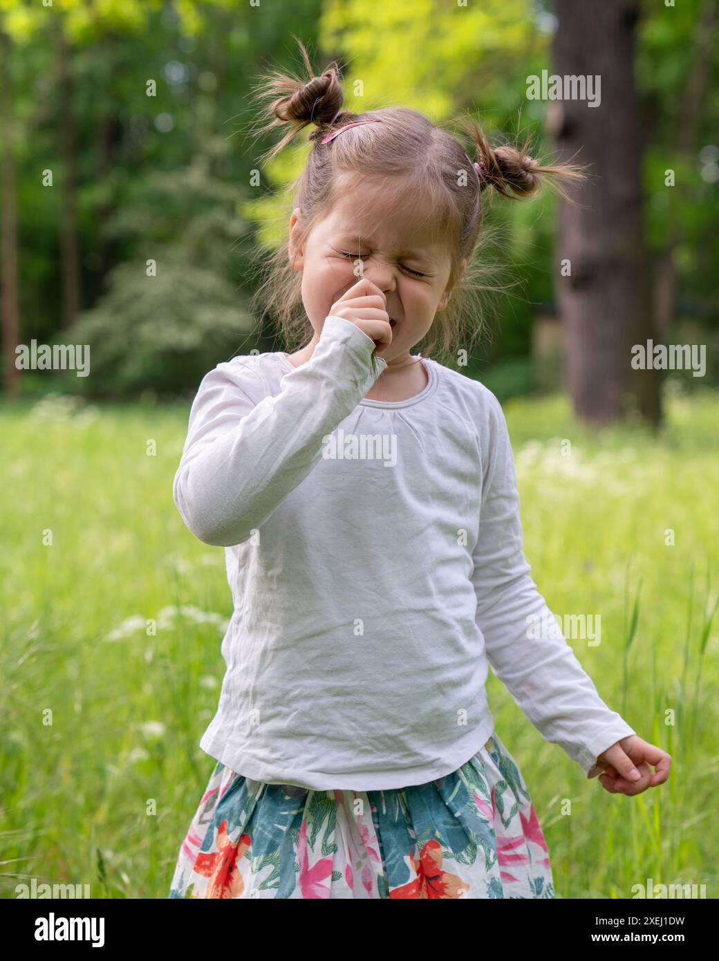 Una bella bambina che cammina nel parco. Ha chiuso ermeticamente gli occhi. Risentimento, delusione, emozioni, tristezza, rabbia, relazioni di pianto Foto Stock