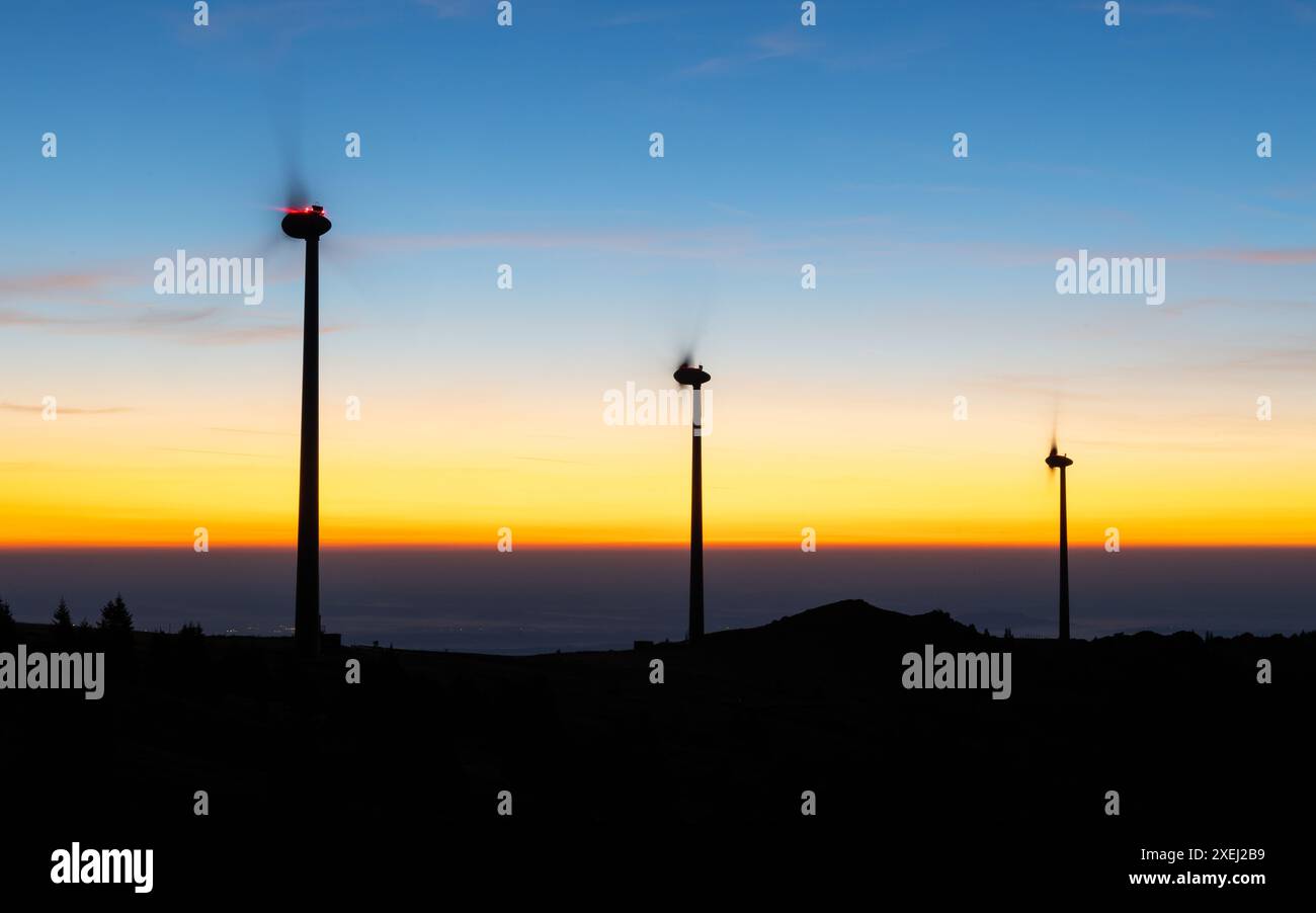 Gruppo di mulini a vento per la produzione di energia elettrica su un crinale di montagna poco prima dell'alba Foto Stock