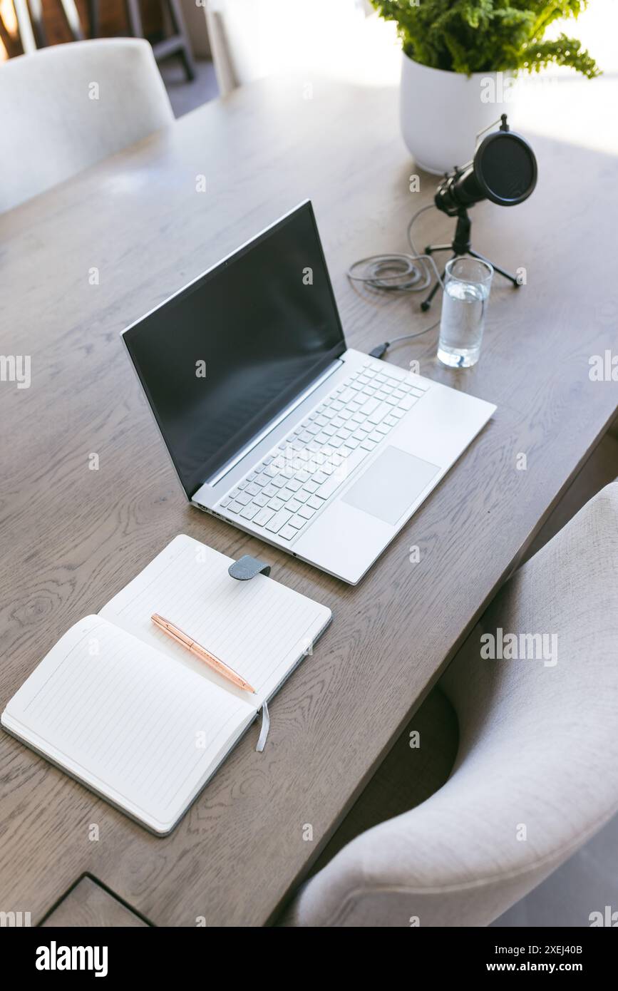 Laptop, notebook e microfono su un tavolo in legno per l'installazione in ufficio domestico Foto Stock