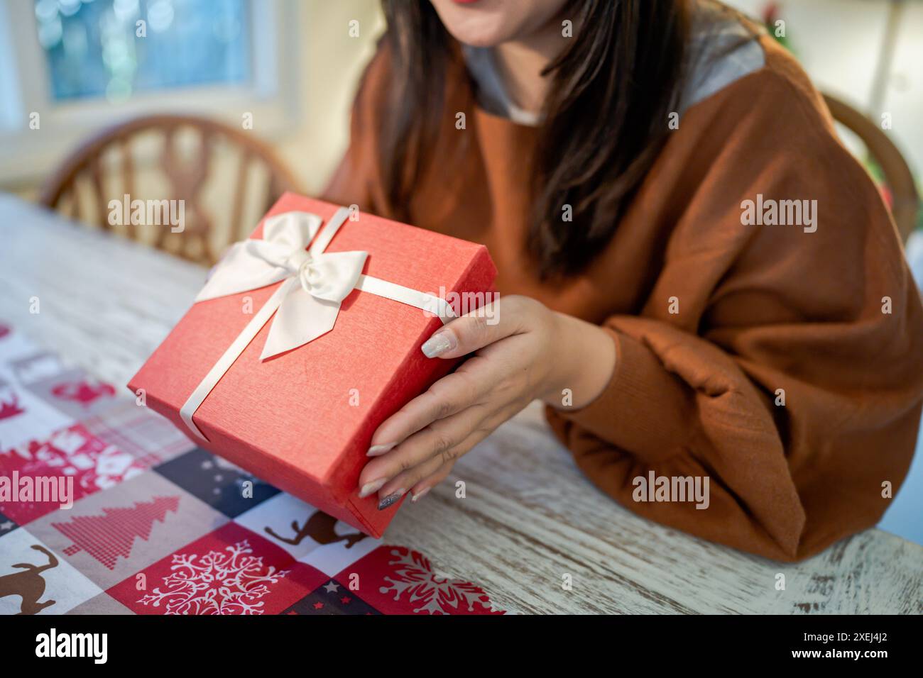 Le mani di una donna asiatica felice ed eccitata tengono in mano una confezione regalo di Natale. Allegra ragazza che porta il regalo di Natale o il compleanno di Natale boxÂ Natale Foto Stock