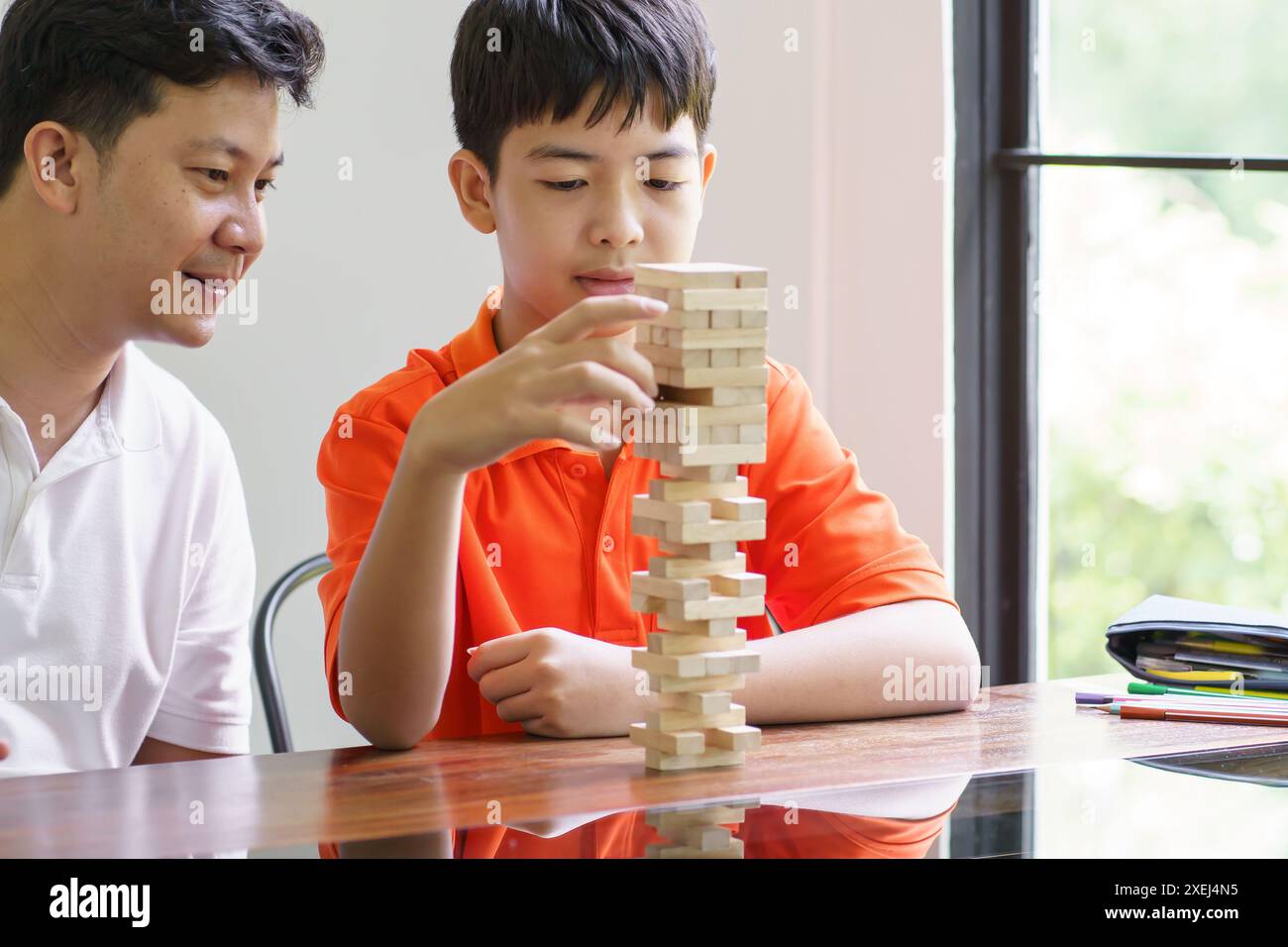 Padre e figlio asiatici che giocano a blocchi di legno bambino Carefree che gioca a blocchi di legno costruttore di costruzioni di blocchi di legno da blocchi con padre Foto Stock