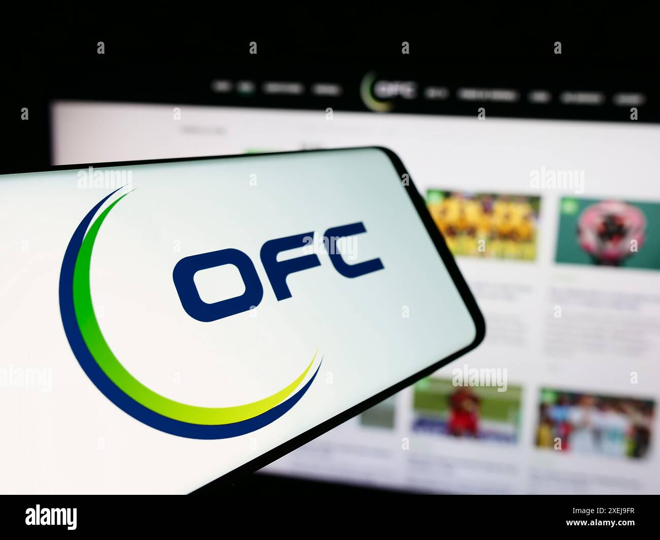 Cellulare con logo dell'associazione Oceania Football Confederation (OFC) davanti al sito web. Mettere a fuoco la parte centrale sinistra del display del telefono. Foto Stock