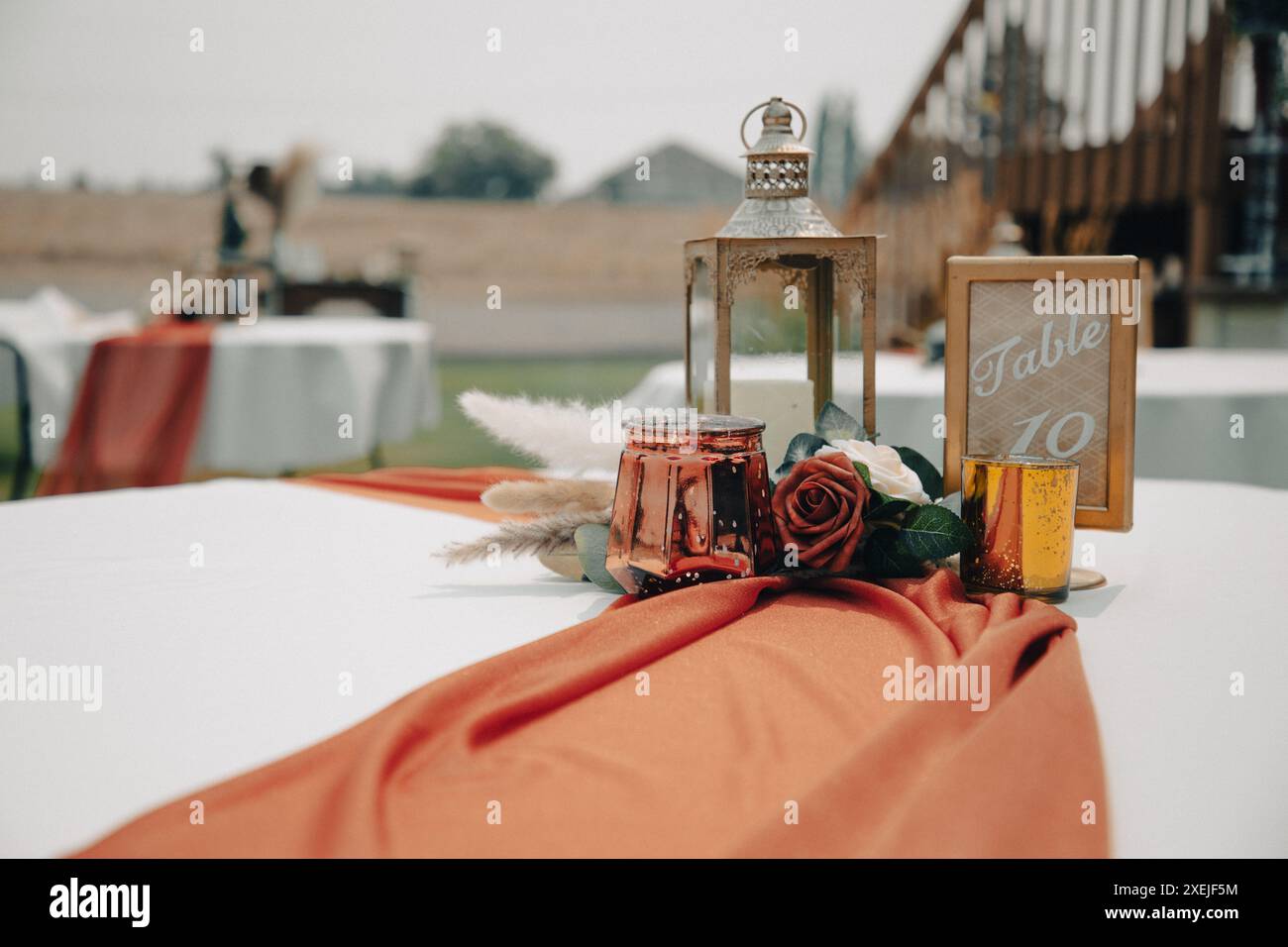 Tavolo per matrimoni all'aperto con lanterna centrale, fiori e. Foto Stock