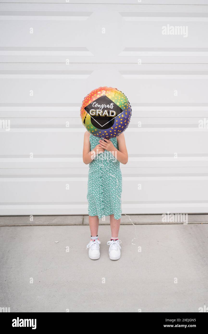 Bambino in piedi con un palloncino graduato che copre la faccia all'esterno Foto Stock