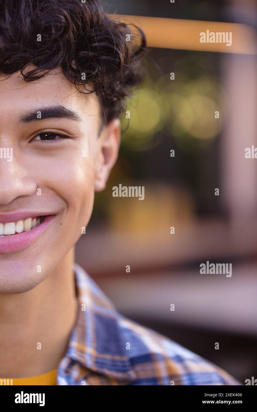 Adolescente sorridente con capelli ricci che indossa una camicia a quadri e un ritratto ravvicinato Foto Stock