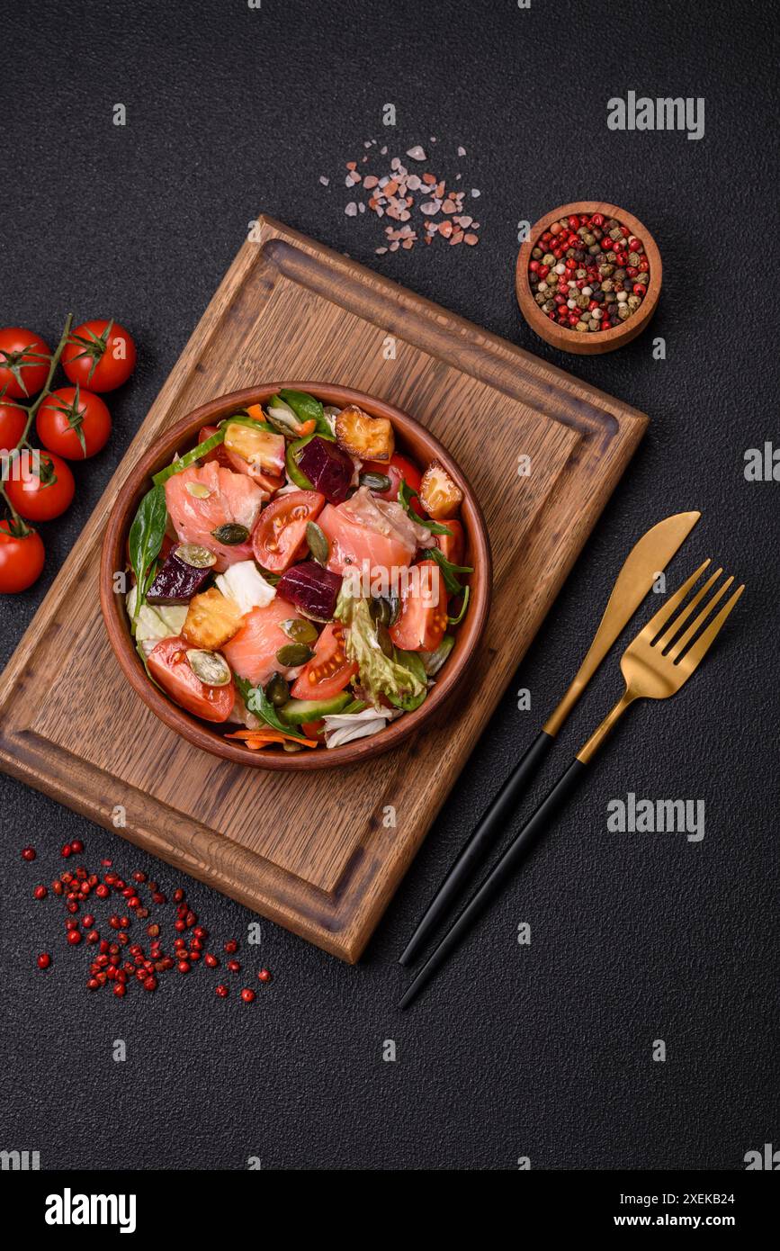 Deliziosa insalata succosa con salmone, pomodori, cetrioli, erbe aromatiche, semi di zucca Foto Stock