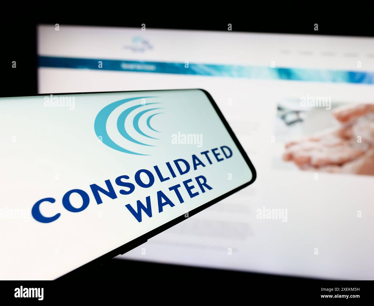 Telefono cellulare con logo della società di desalinizzazione dell'acqua di mare Consolidated Water Co. Ltd. Davanti al sito Web. Messa a fuoco al centro del display del telefono. Foto Stock