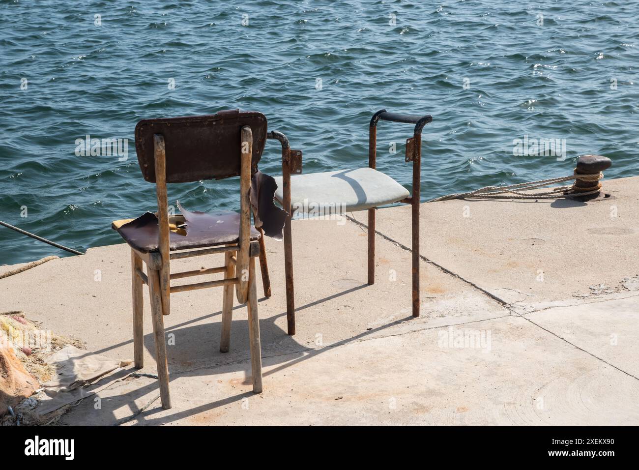 Vecchie sedie grunge maldate sul molo di pesca a bordo di una vecchia barca da pesca in legno Foto Stock