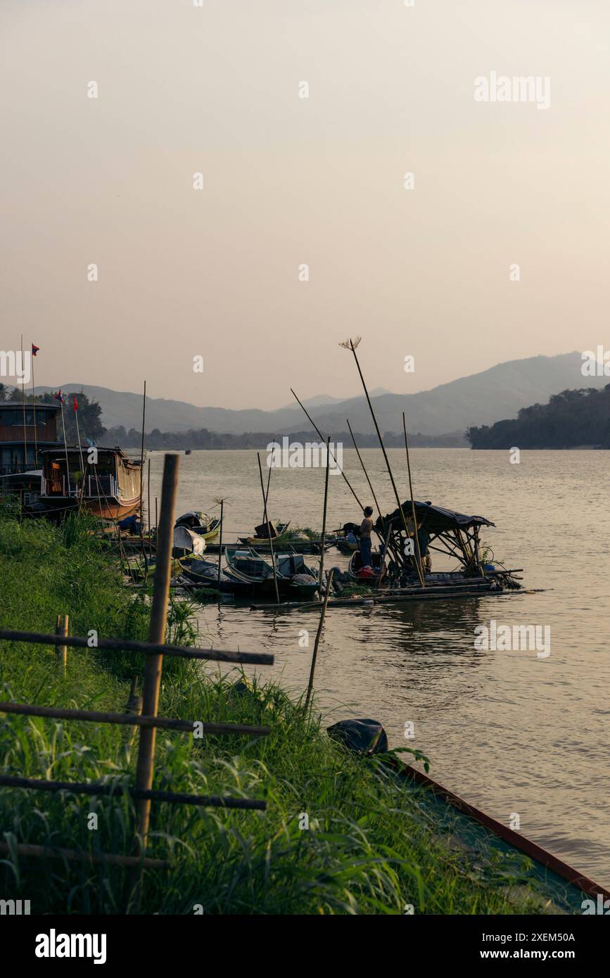 Vita lungo un fiume al crepuscolo a Luang Prabang, Laos; Luang Prabang, provincia di Luang Prabang, Laos Foto Stock