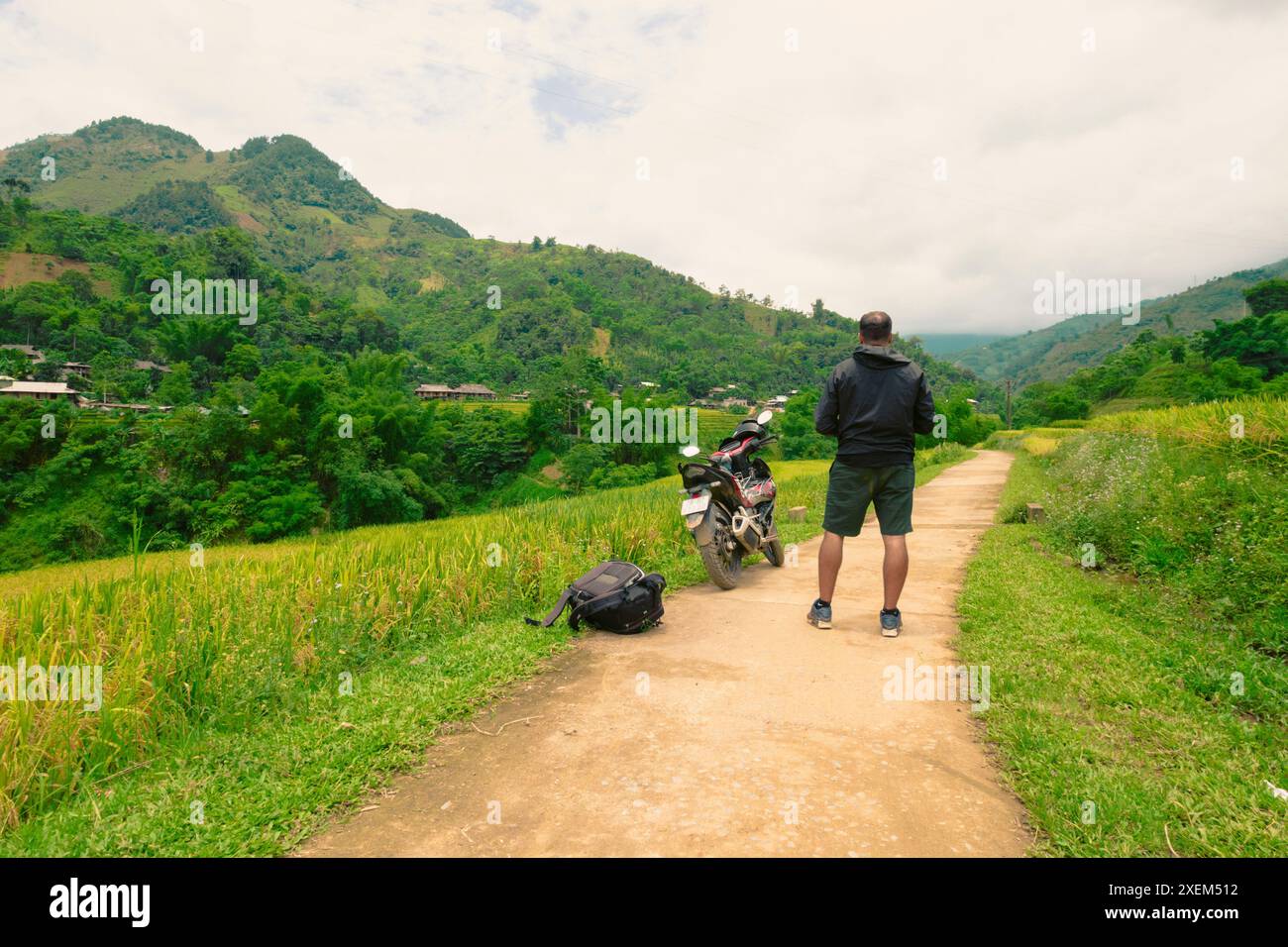 Un uomo in viaggio in moto si ferma su una strada di campagna a Yen Bai, Vietnam; tram Tau, tram Tau District, Yen Bai, Vietnam Foto Stock