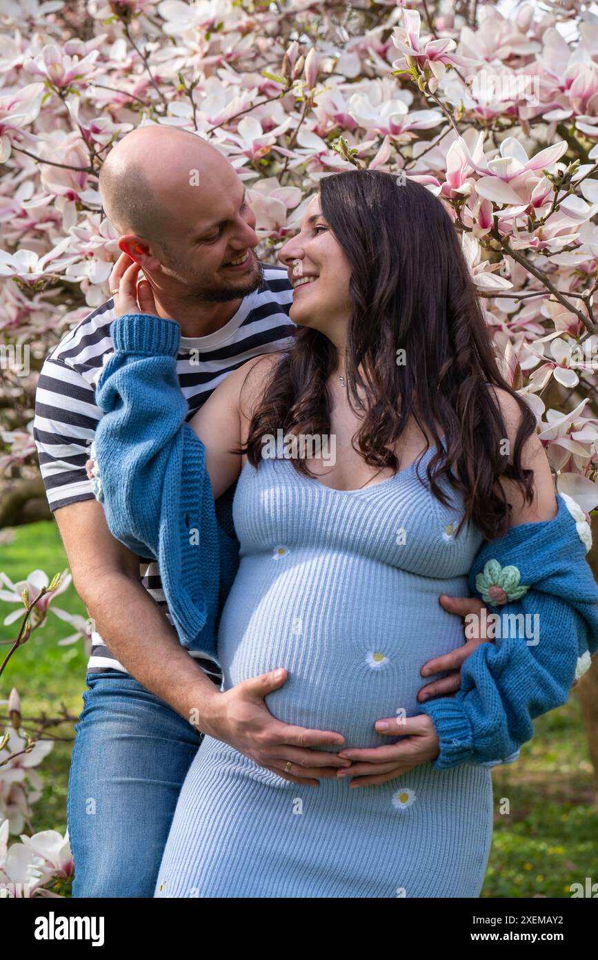 Famiglia felice che aspetta un bambino e che esprime amore l'uno per l'altro Un uomo abbraccia con tenerezza la moglie incinta. Gravidanza, relazioni familiari Foto Stock