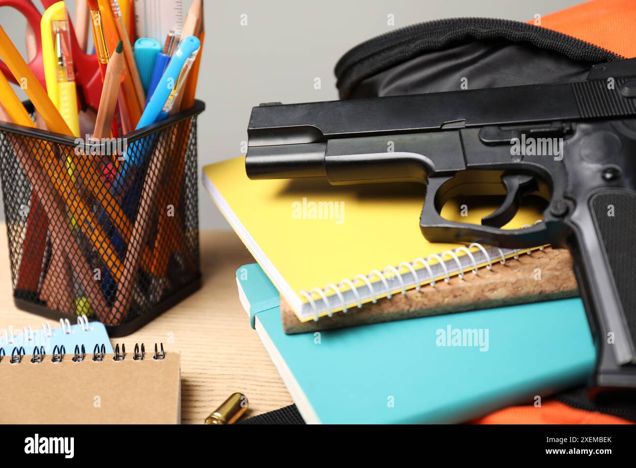 Pistola, proiettili e cancelleria scolastica su un tavolo di legno, primo piano Foto Stock