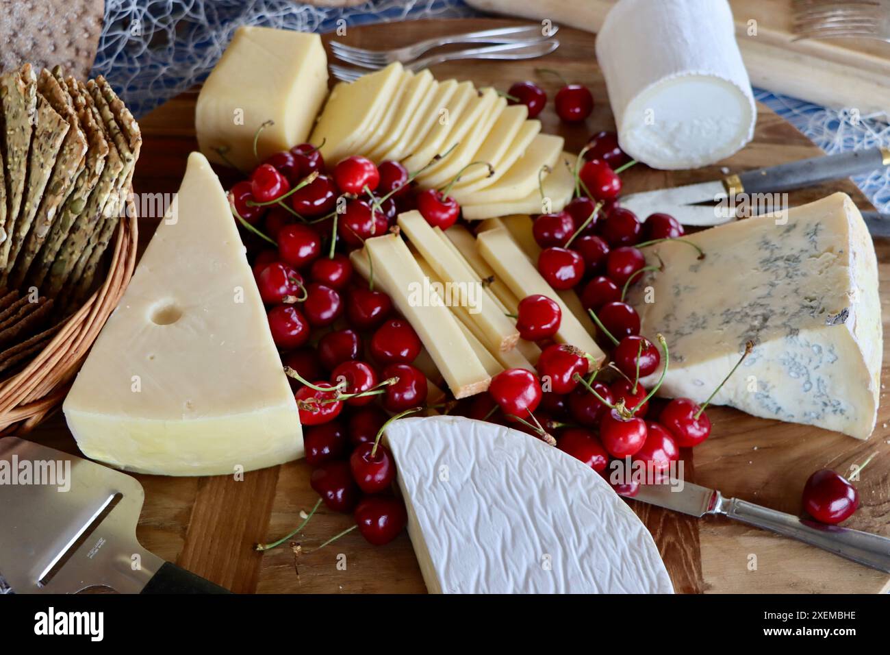 Tagliere di formaggi con selezione di formaggi e razze, decorato con ciliegie su buffet di mezza estate, giugno 2024 Foto Stock