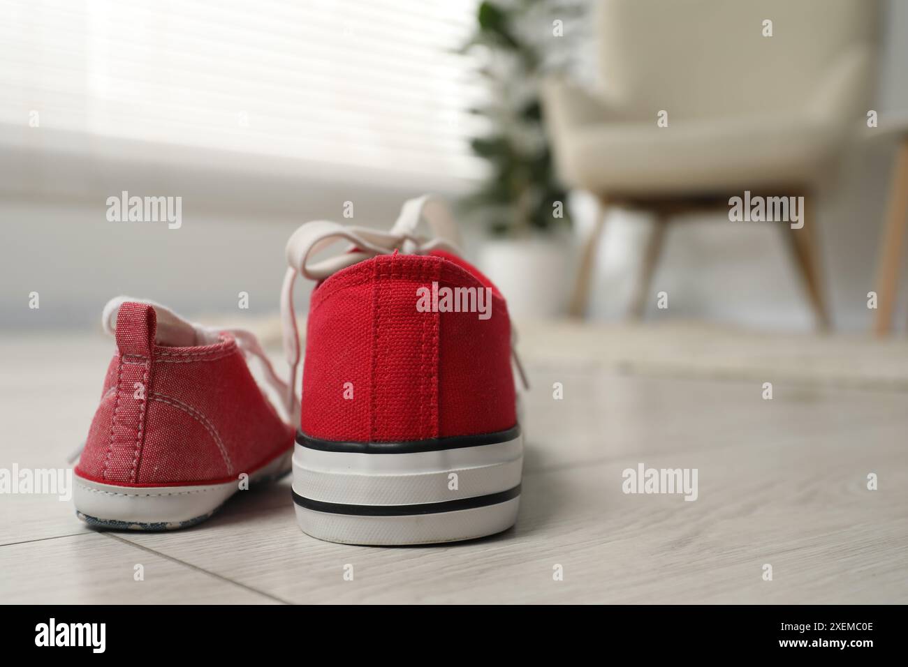 Sneaker grandi e piccole su pavimento in interni, spazio per il testo Foto Stock