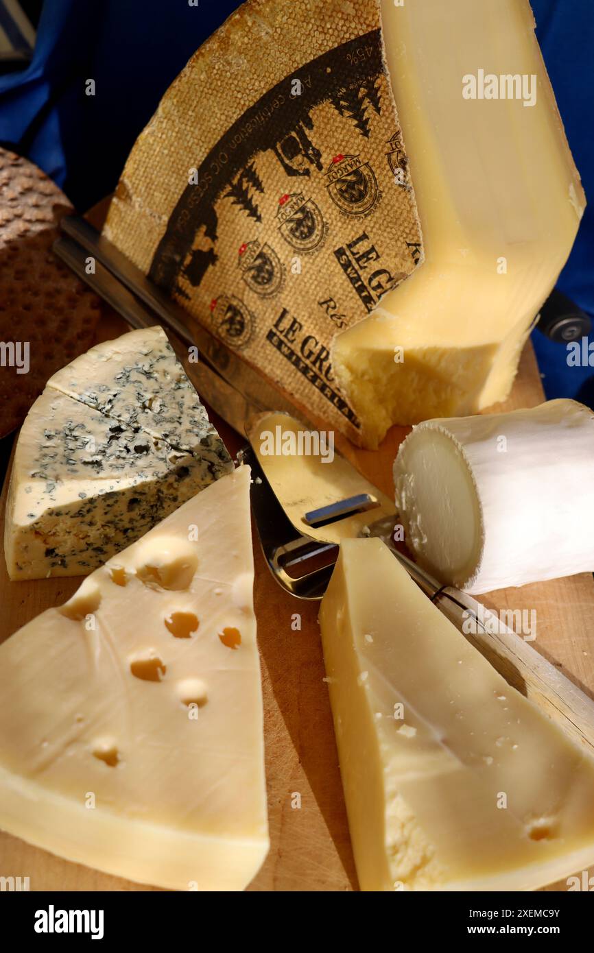 Un enorme pezzetto di gruyere con formaggio di capra, formaggio blu ed emmenthal su un tagliere di formaggio su buffet di mezza estate, giugno 2024 Foto Stock