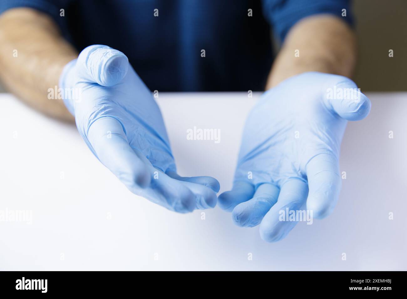 Espressiva insieme le mani di un medico o di un infermiere che indossano guanti in lattice su un tavolo da ufficio bianco. Posiziona oggetto. Foto Stock