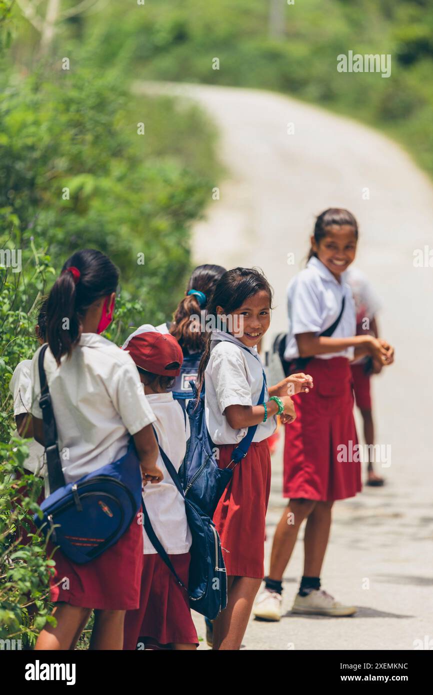 I bambini delle scuole stanno insieme su una strada in una giornata di sole nella West Sumba Regency, Indonesia; West Sumba Regency, East Nusa Tenggara, Indonesia Foto Stock
