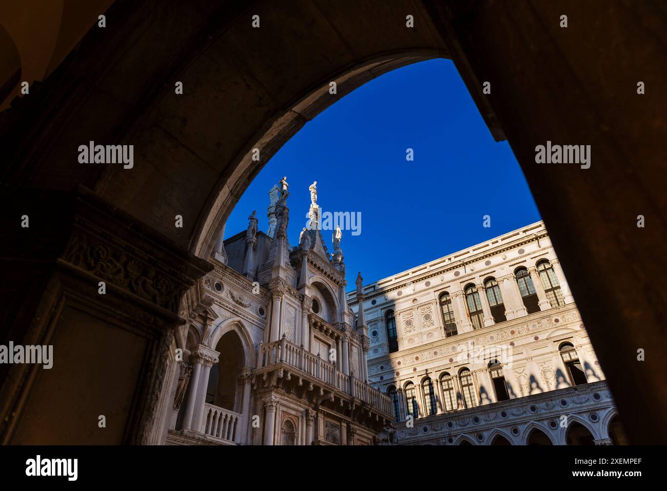 Vista incorniciata di un dettaglio dell'architettura gotica veneziana del Palazzo Ducale contro un cielo blu; Venezia, Veneto, Italia Foto Stock