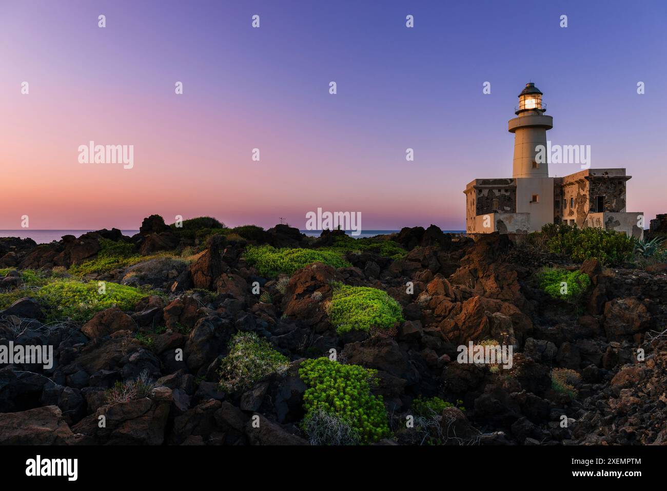 Vista ravvicinata del paesaggio costiero e del faro di Faro di Punta Spadillo nel Parco Nazionale dell'Isola di Pantelleria al crepuscolo Foto Stock