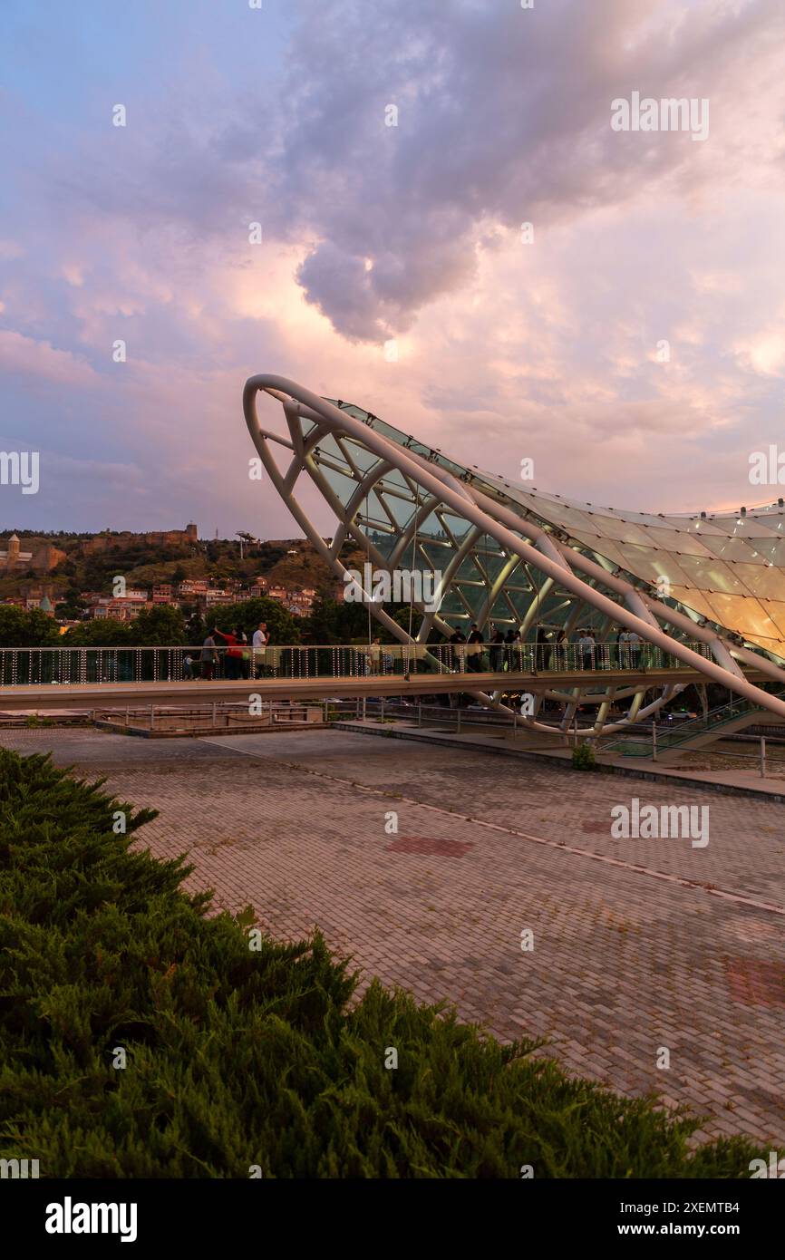 Tbilisi, Georgia - 16 giugno 2024: Il Ponte della Pace è un ponte pedonale a forma di arco, una costruzione in acciaio e vetro sul fiume Kura, che collega t Foto Stock