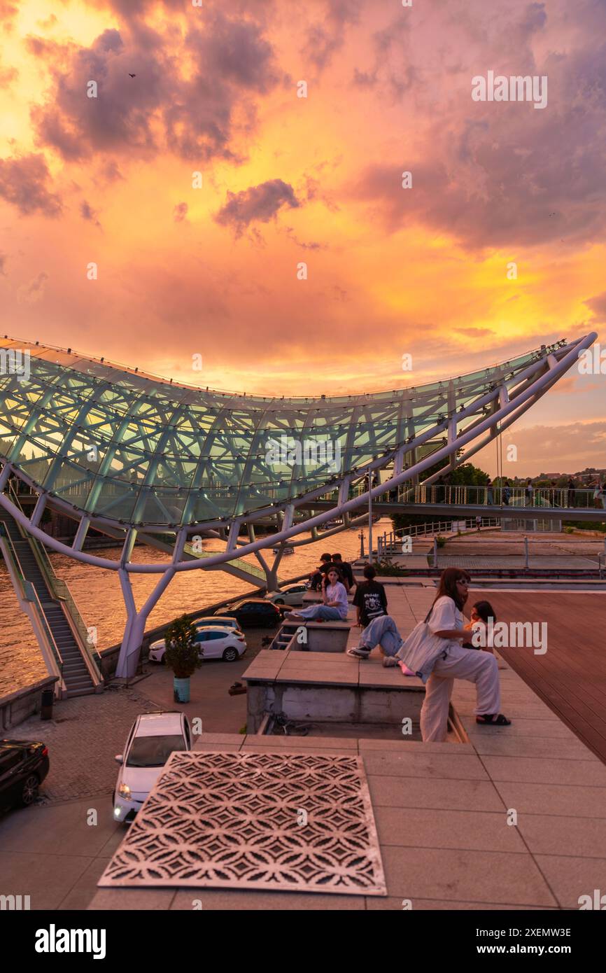 Tbilisi, Georgia - 16 giugno 2024: Il Ponte della Pace è un ponte pedonale a forma di arco, una costruzione in acciaio e vetro sul fiume Kura, che collega t Foto Stock
