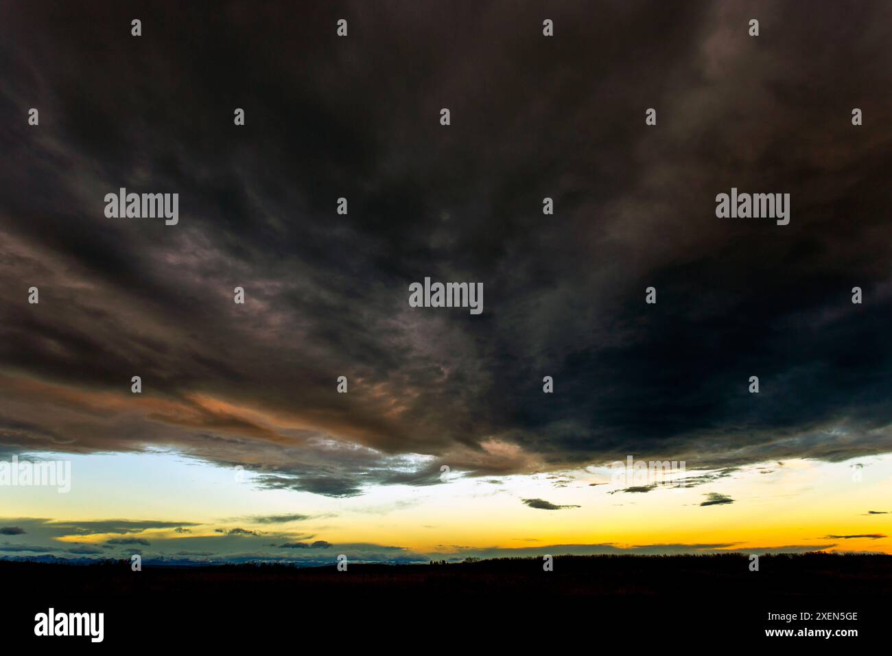 Spettacolari nuvole di tempesta con una pausa nella copertura delle nuvole e il caldo bagliore del tramonto; Calgary, Alberta, Canada Foto Stock