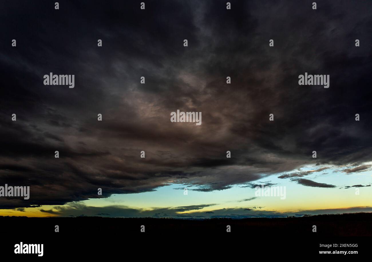 Spettacolari nuvole di tempesta con una pausa nella copertura delle nuvole e il caldo bagliore del tramonto; Calgary, Alberta, Canada Foto Stock