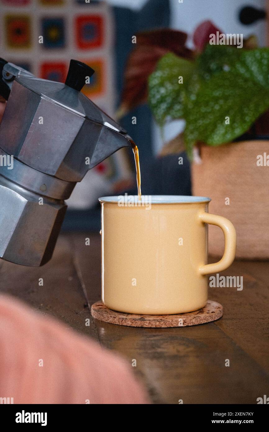 Versare il caffè da una moka in una tazza di smalto Foto Stock