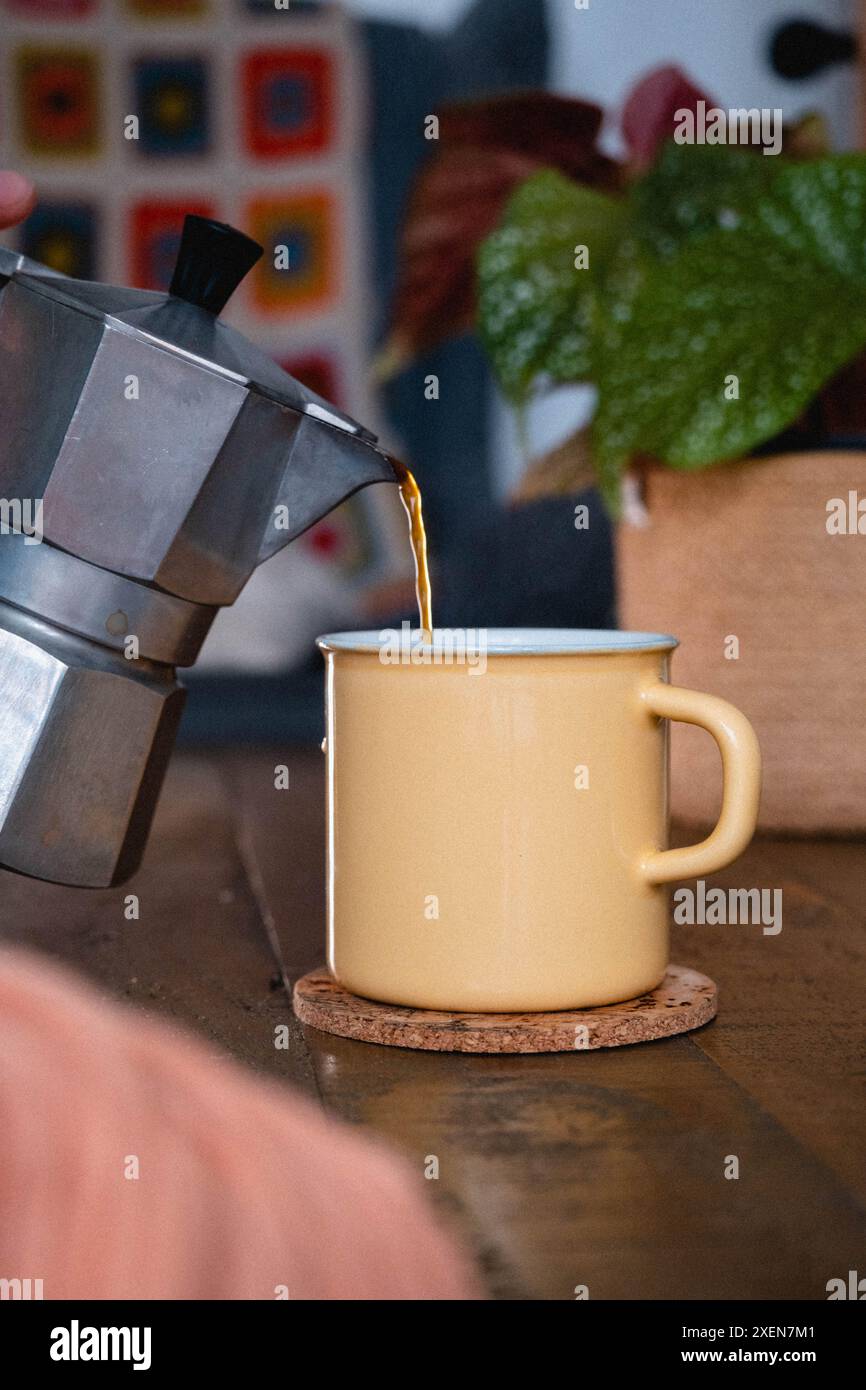 Versare il caffè da una moka in una tazza di smalto Foto Stock