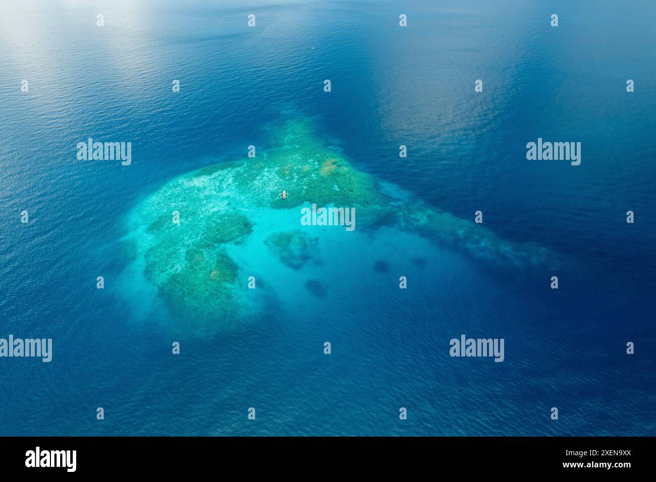 La barca solitaria viaggia su una barriera corallina e sulle acque turchesi dell'oceano nel Parco Nazionale Kepulauan Togean; Wakai, Sulawesi centrale, Indonesia Foto Stock