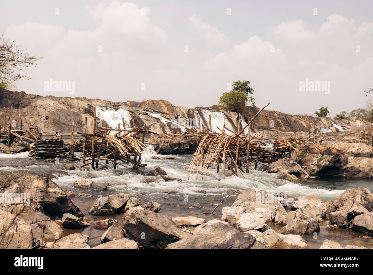 Cascate su un paesaggio roccioso con strutture trascurate su Don Khon, Laos; Don Khon, provincia di Champasak, Laos Foto Stock