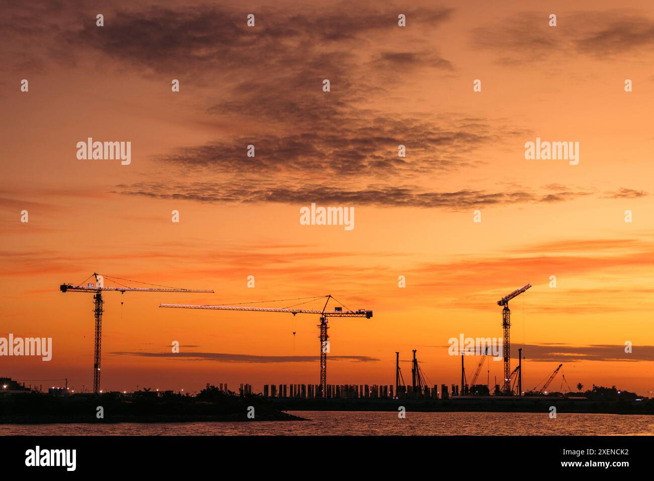 Gru sagomate nel porto lungo il passaggio marittimo dello stretto di Makassar al tramonto a Sulawesi, Indonesia; Makassar, Sulawesi meridionale, Indonesia Foto Stock