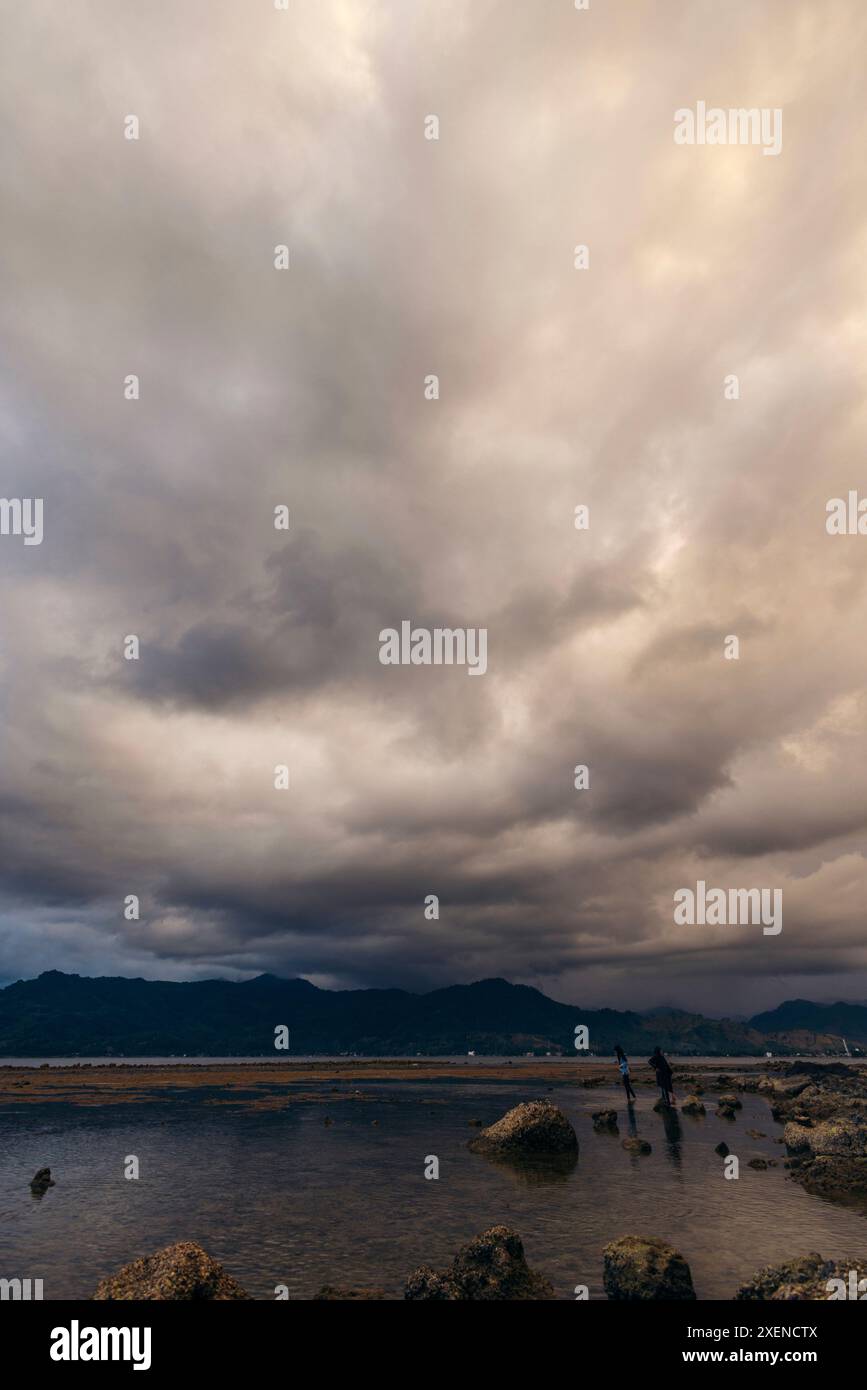 Isola di Dutungan sotto un cielo nuvoloso drammatico; isola di Dutungan, Kecamatan Mallusetasi, Kabupaten Barru, Sulawesi Selatan, Indonesia Foto Stock