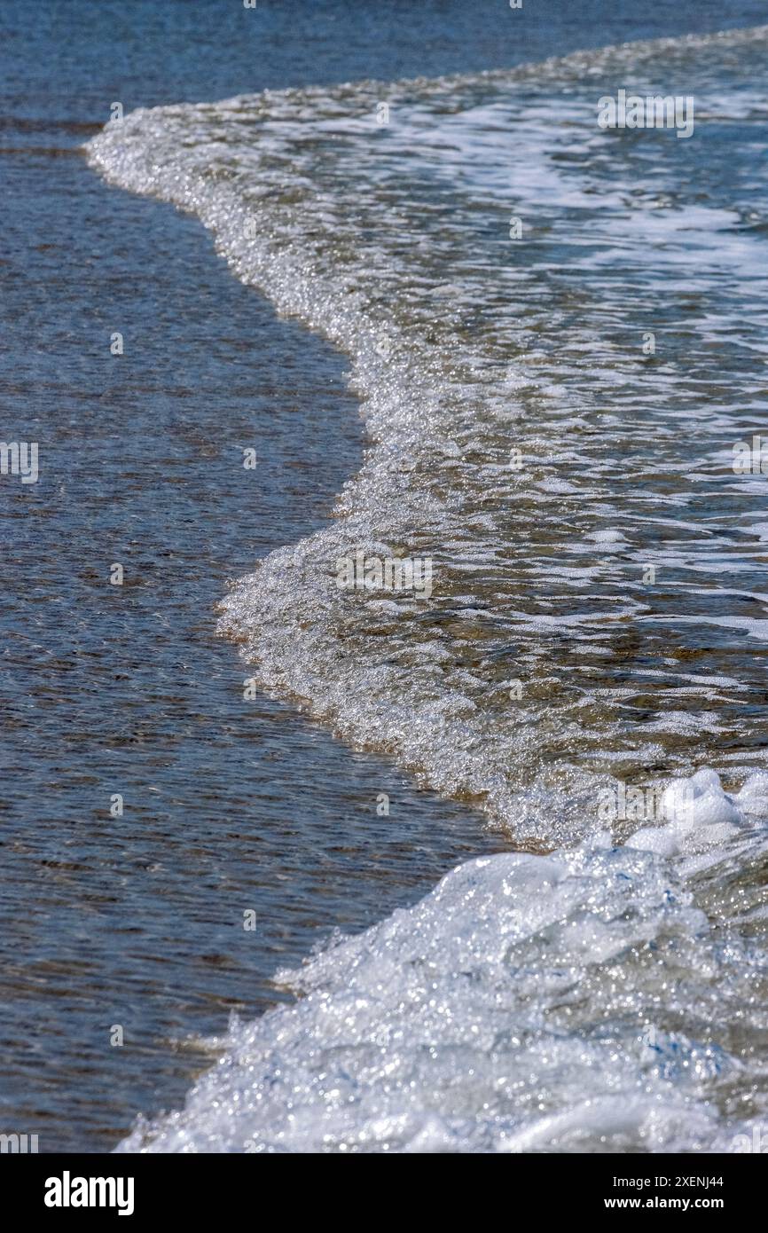 Acqua scintillante che si lava sulla spiaggia Foto Stock