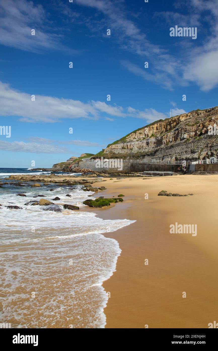 Una bella giornata a Newcastle Beach guardando verso sud verso la scogliera. Questa spiaggia interna della città è una carta da traino nella città più antica dell'Australia, un paio di persone Foto Stock