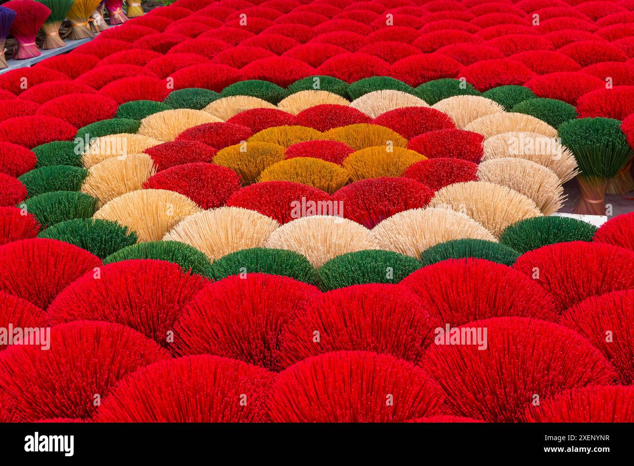 Il vibrante incenso è disposto a terra per asciugare al sole a Quang Phu Cau, Ung Hoa, Vietnam del Nord, Asia a giugno - bastoncini di incenso rossi, gialli e verdi Foto Stock