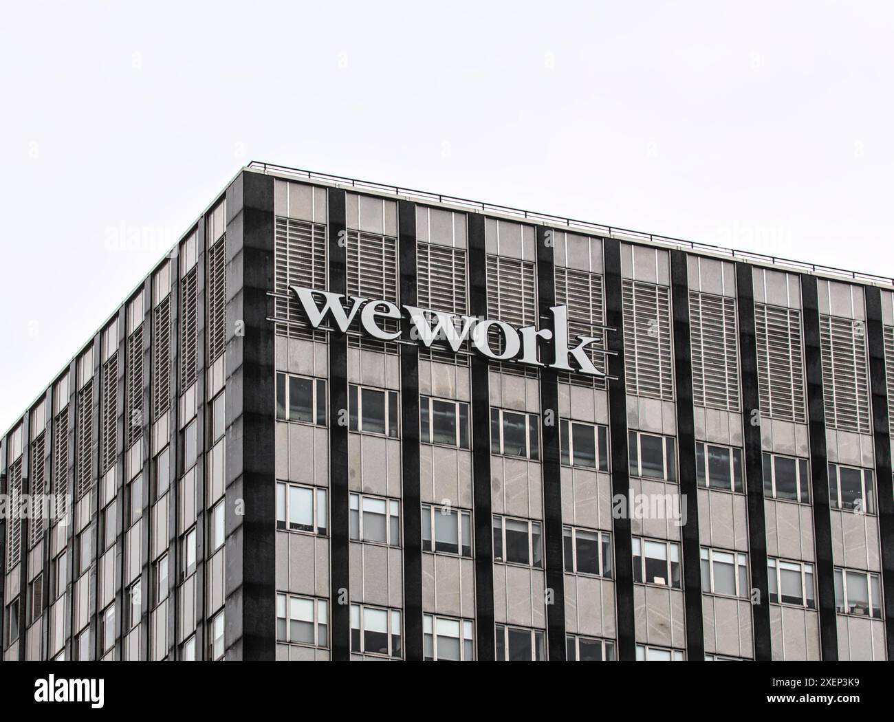 Brooklyn, New York - 15 gennaio 2023: Cartello della compagnia WeWork per lo spazio di coworking su un alto edificio per uffici con sfondo grigio a Brooklyn, New York City. Foto Stock