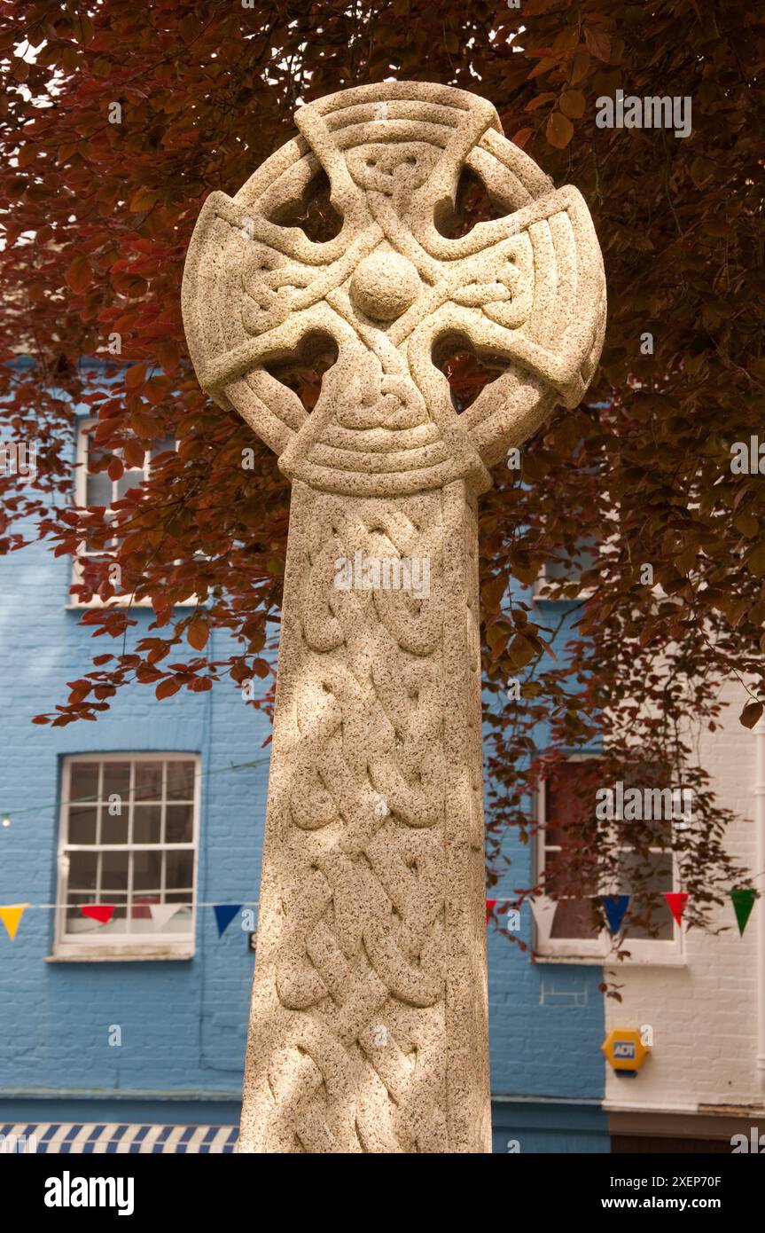 Croce celtica, chiesa di San Fimbarro, Fowey, Cornovaglia, Regno Unito - case colorate sullo sfondo e foglie rosse dall'albero. Foto Stock