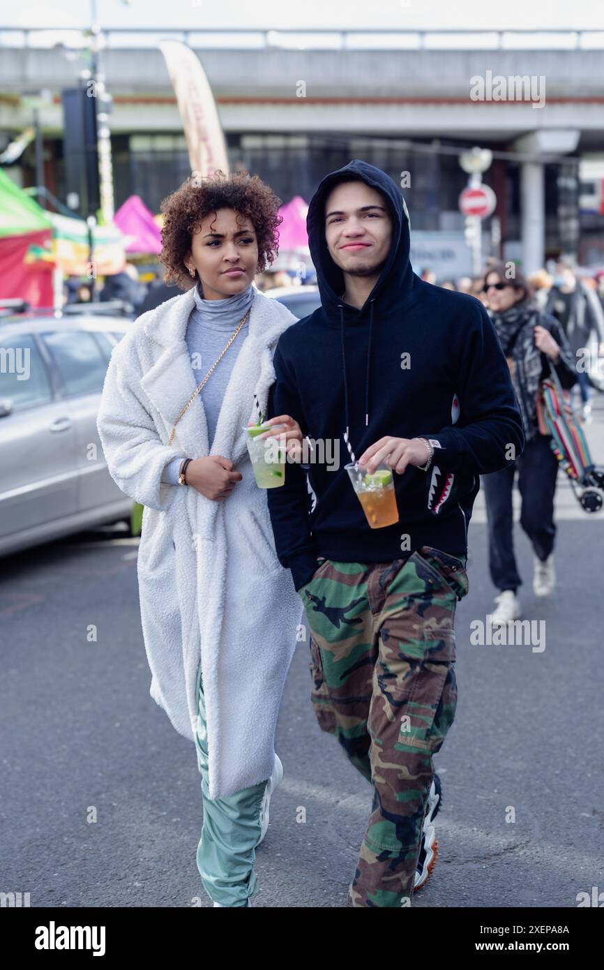 Un paio camminano braccio in braccio attraverso un mercato di strada Foto Stock
