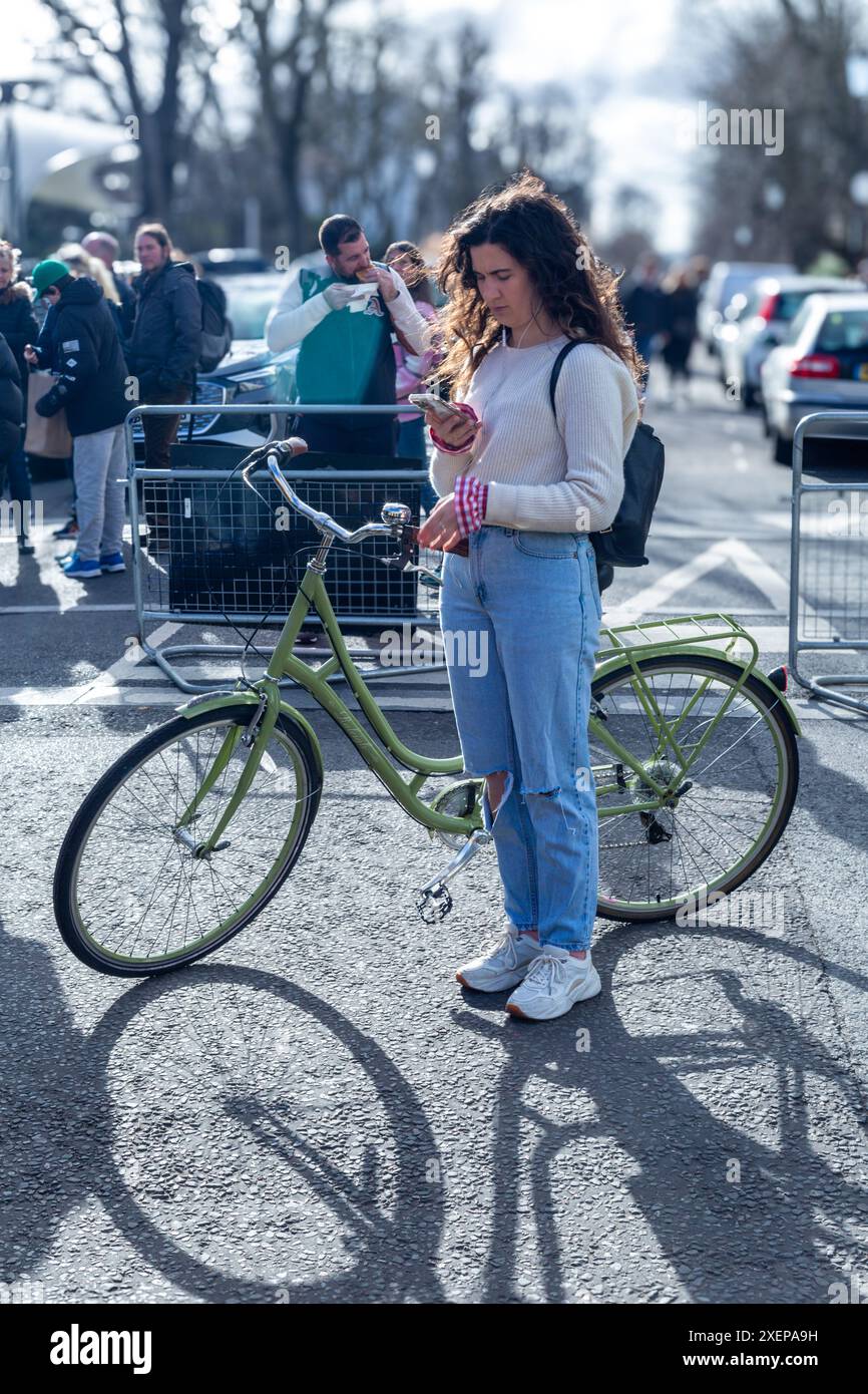 Una donna sta con la bici mentre controlla i messaggi sul telefono Foto Stock