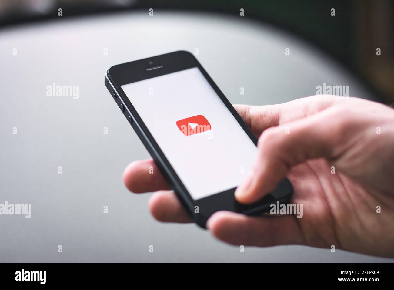 Ondon, Regno Unito - giugno 27 2024: Primo piano di una mano che tiene in mano uno smartphone mobile con una schermata bianca che mostra il logo dell'app YouTube con spazio di copia Foto Stock