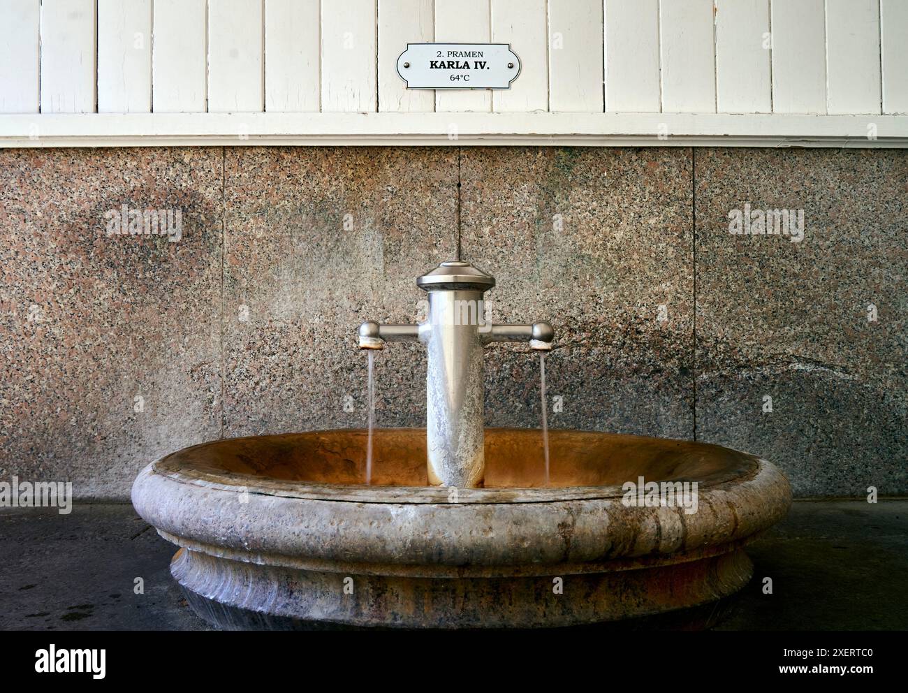 Karlsbad, Cechia, 10 giugno 2024: La sorgente calda di Karla IV scarica la sua acqua curativa in un bacino di pietra rotondo dove si formano depositi di ferro Foto Stock