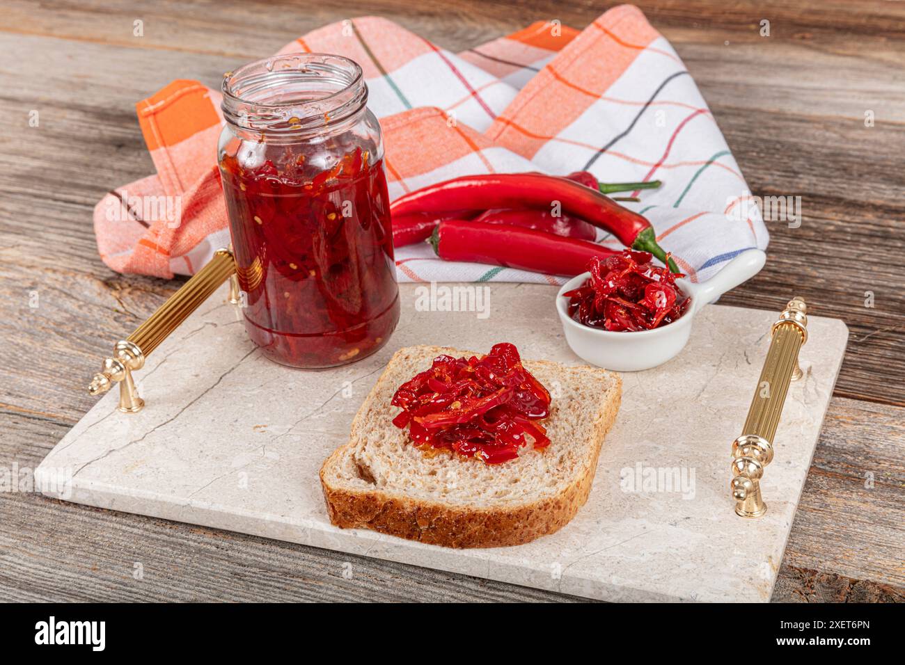 Marmellata di peperoni caldi. Gelatina al pepe nel vaso di vetro sul tavolo. Marmellata di peperoni di paprika e paprika. pane tostato e marmellata di peperoni rossi. su sfondo chiaro. Foto Stock